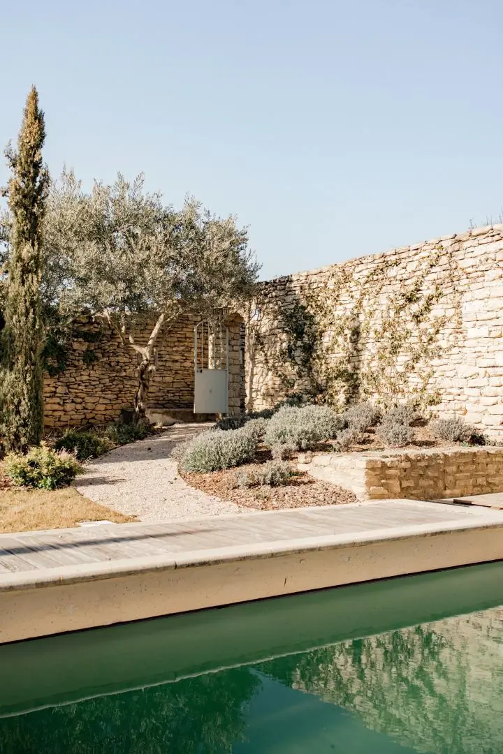 Maison provençale en pierre avec jardin et bassin, reflet du savoir-faire et du soin Pirotte en Luberon.