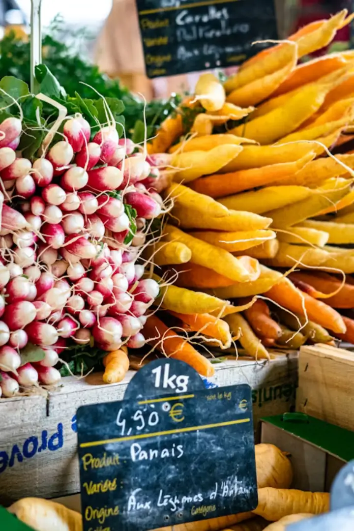 Gros plan sur des bottes de radis frais et des panais bio sur un marché traditionnel du Luberon en Provence.
