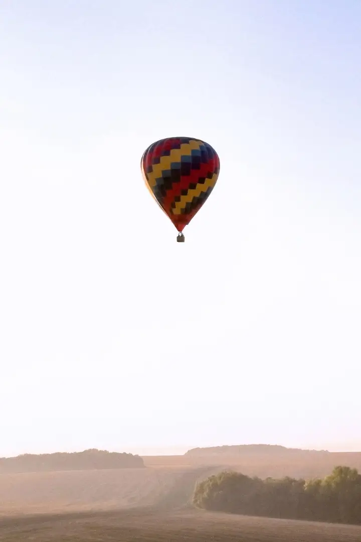 Montgolfière colorée dans un ciel clair au-dessus de champs